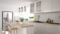 A kitchen with white, modern cabinetry and an island with three hanging lights over it.